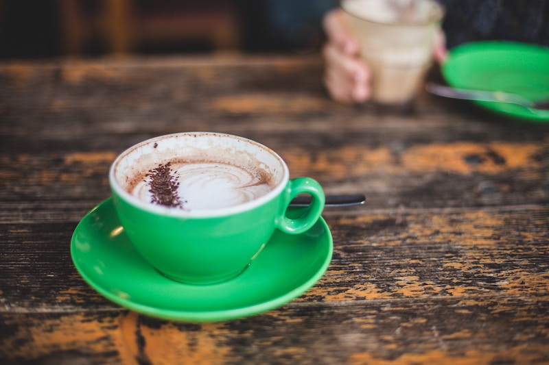 Lone green cup filled with a capacinno